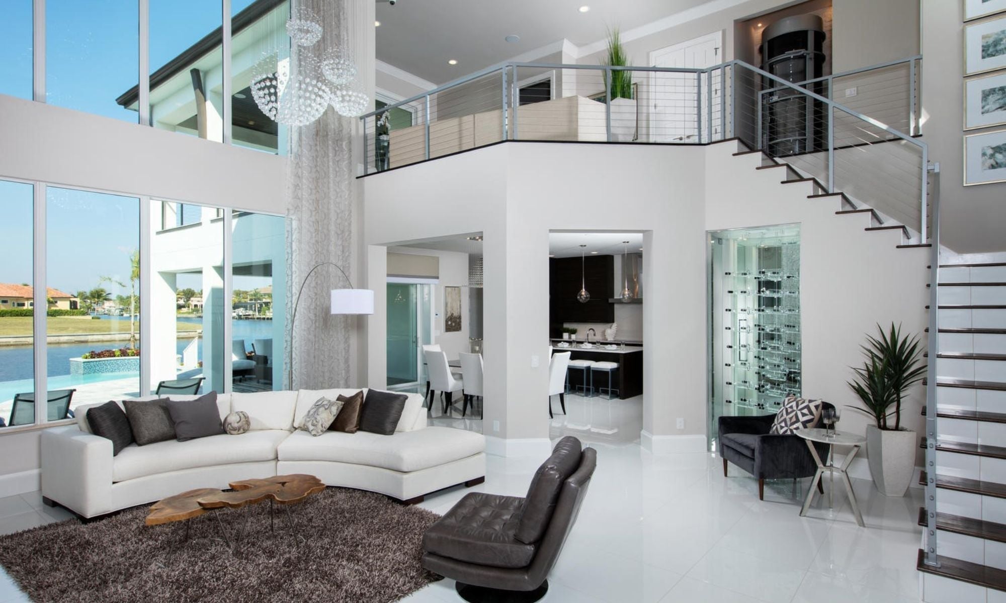 Modern living room with glass wine cellar, luxury wine racks, and large windows overlooking pool