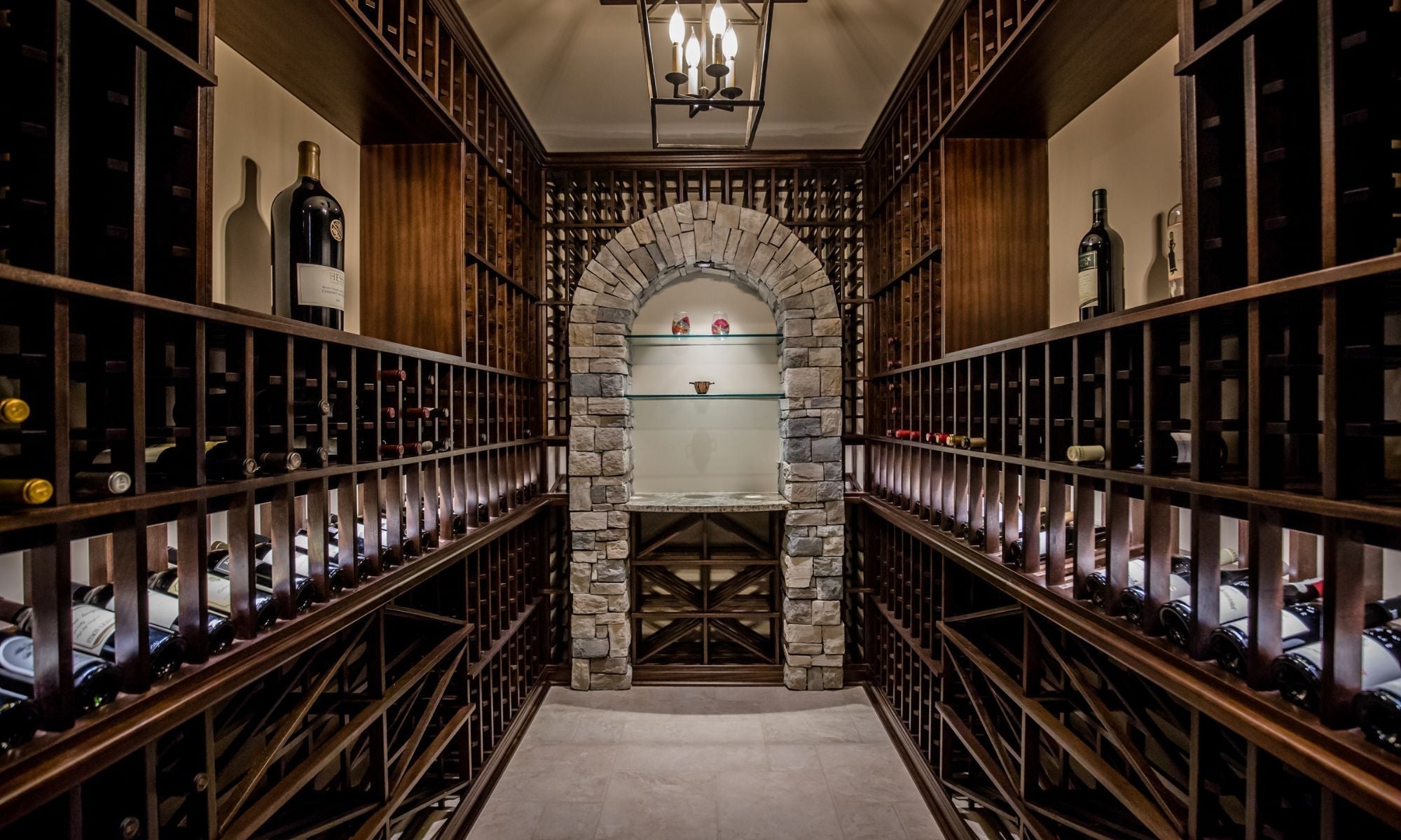 Luxury wine cellar with angled wooden wine racks, stone arch, and glass display shelves