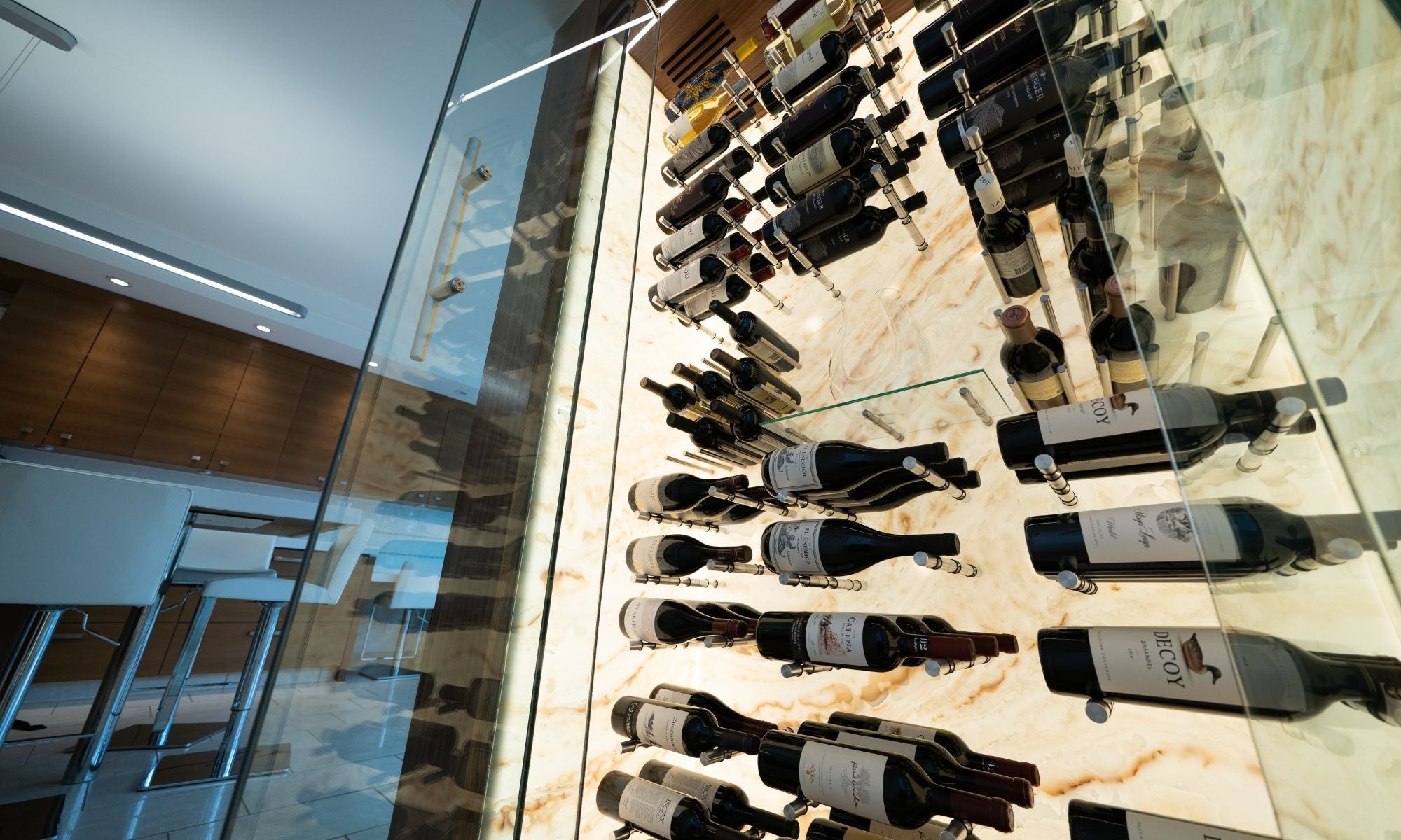 Modern glass wine closet with backlit marble wall and horizontal wine bottle racks