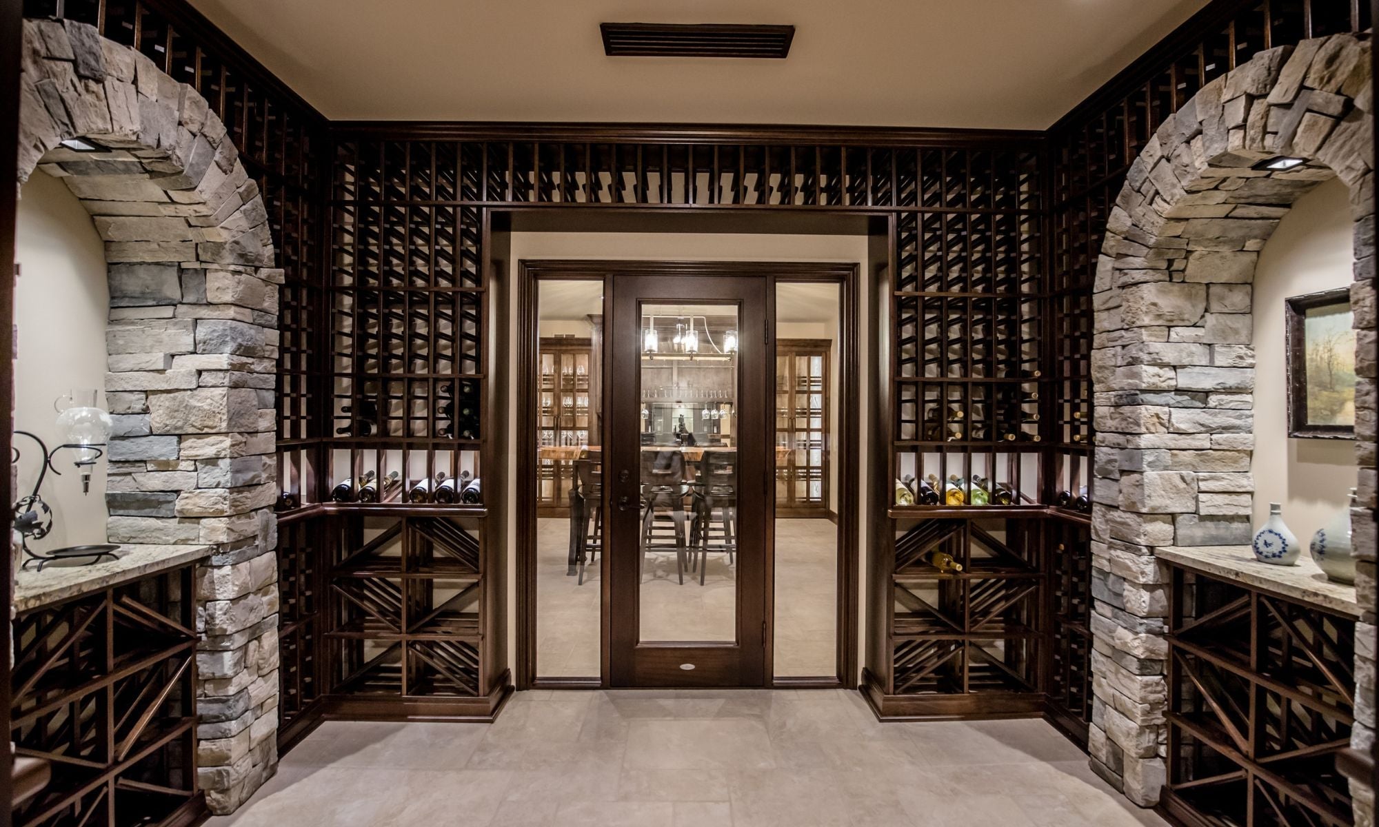 Luxury wine cellar with wooden racks, glass door, and stone archway, showcasing wine storage.