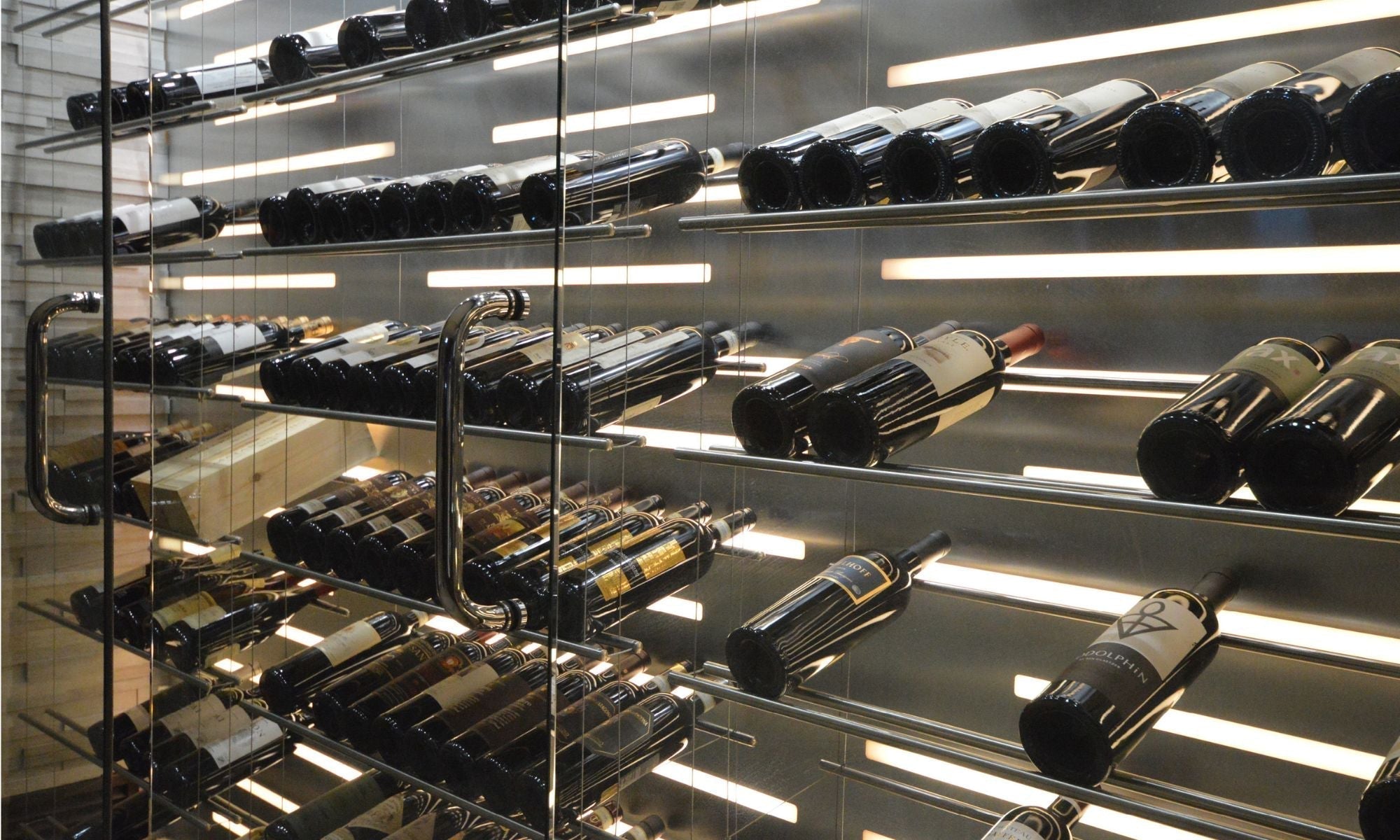 Modern wine storage cabinet with glass doors, chrome racks, and backlit shelves displaying wine bottles