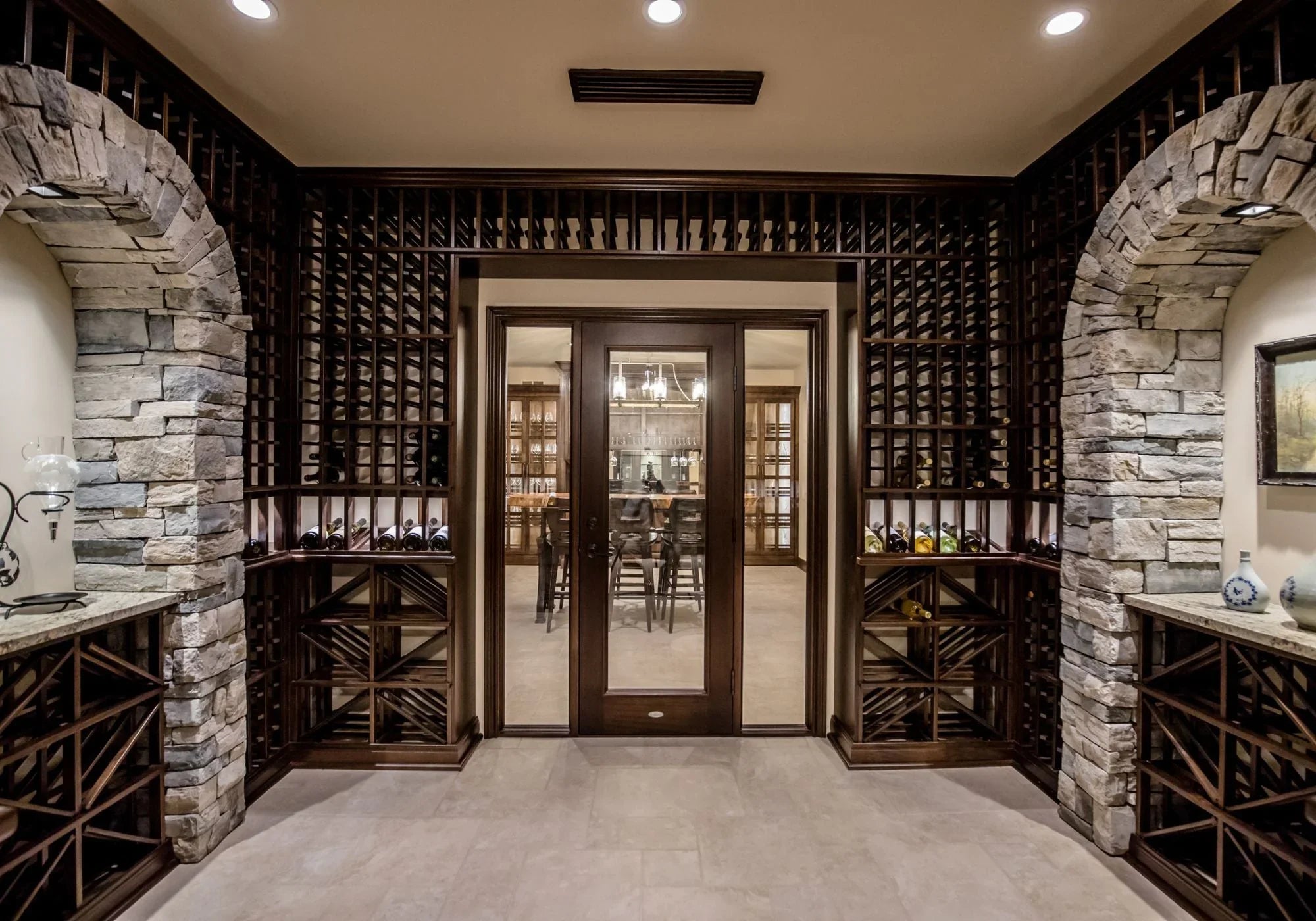 Luxury custom wine cellar with dark wood racks, stone archways, and glass doors