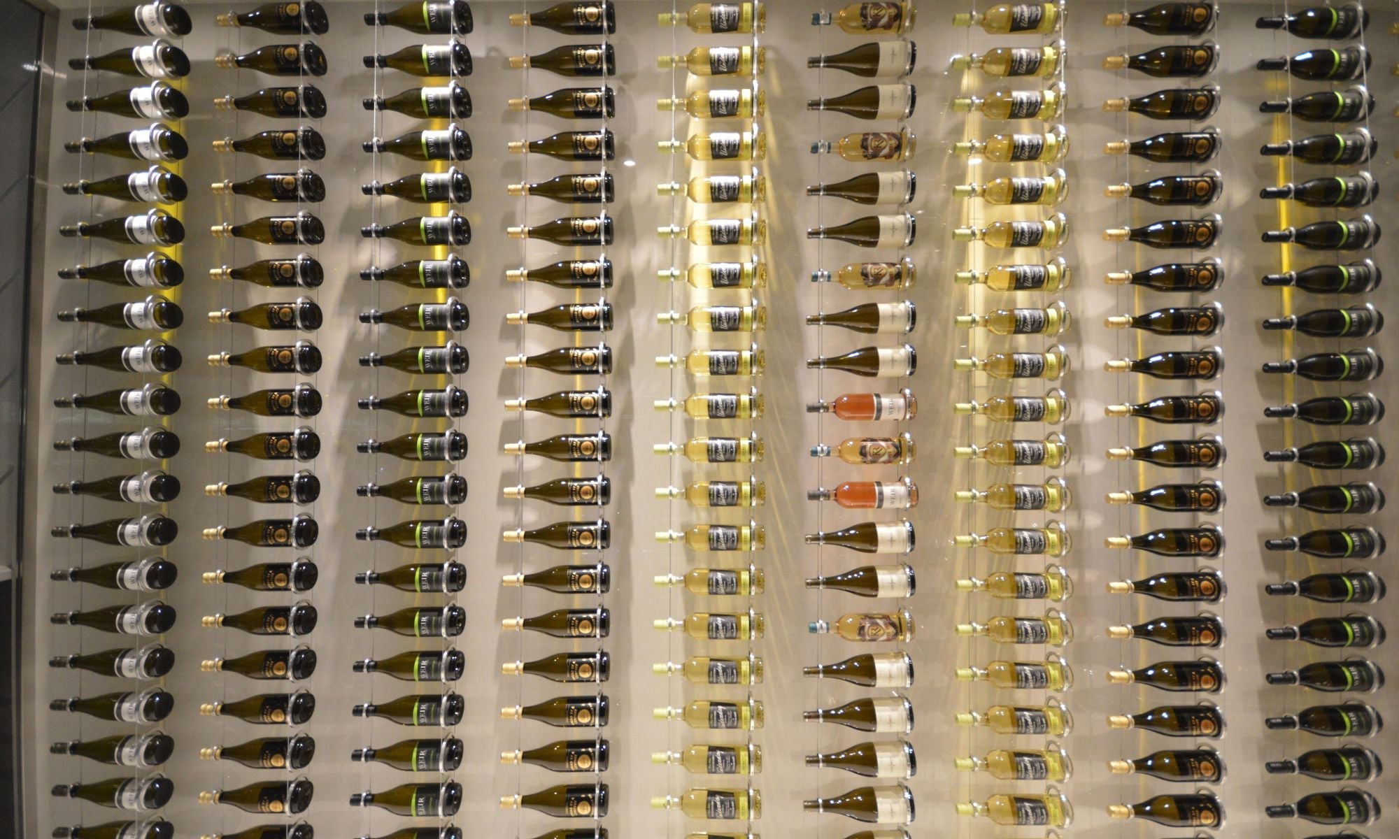Modern wall-mounted wine racks displaying assorted wine bottles in a custom cellar