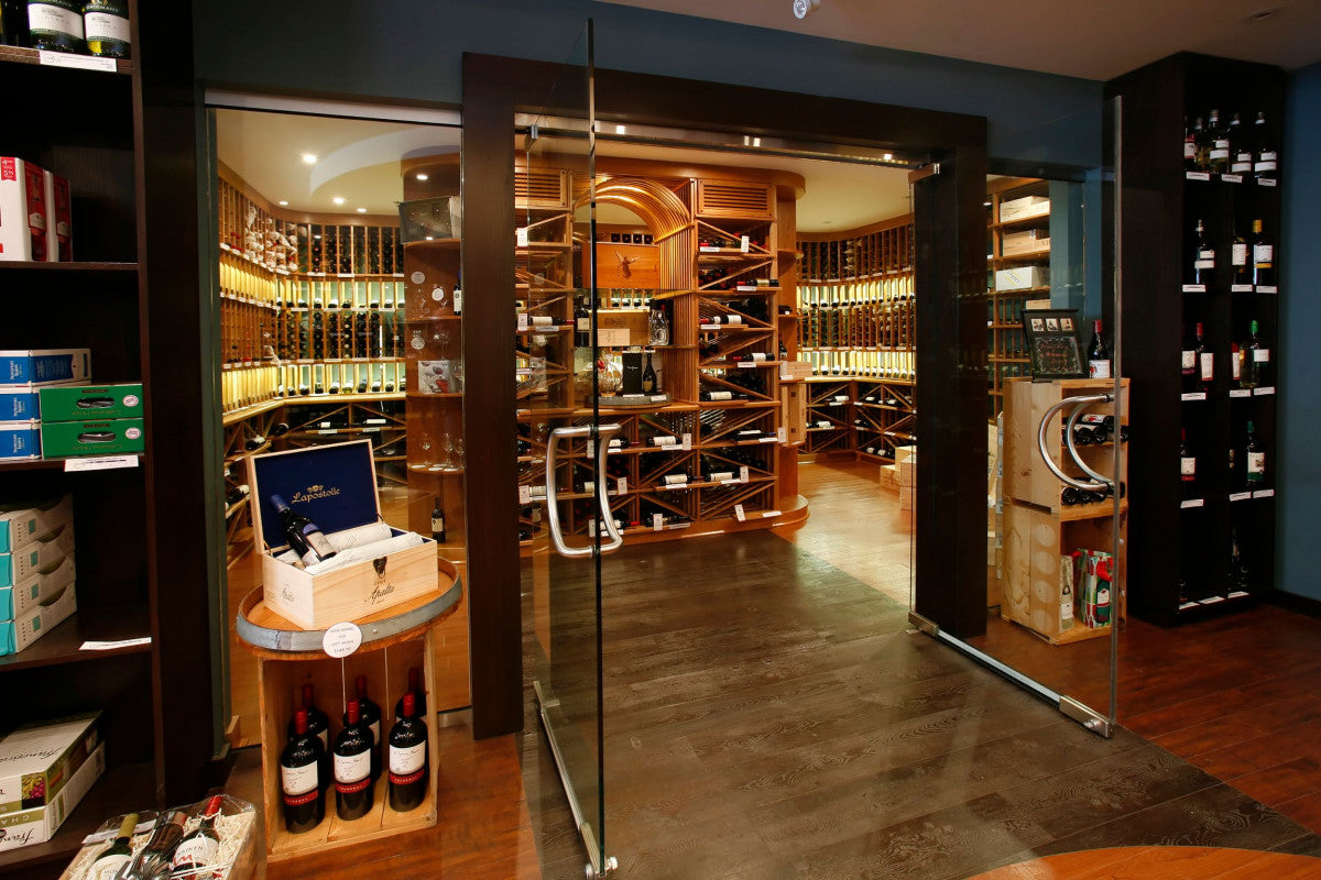 Luxury glass-enclosed wine cellar with wooden racks and premium wine bottle displays