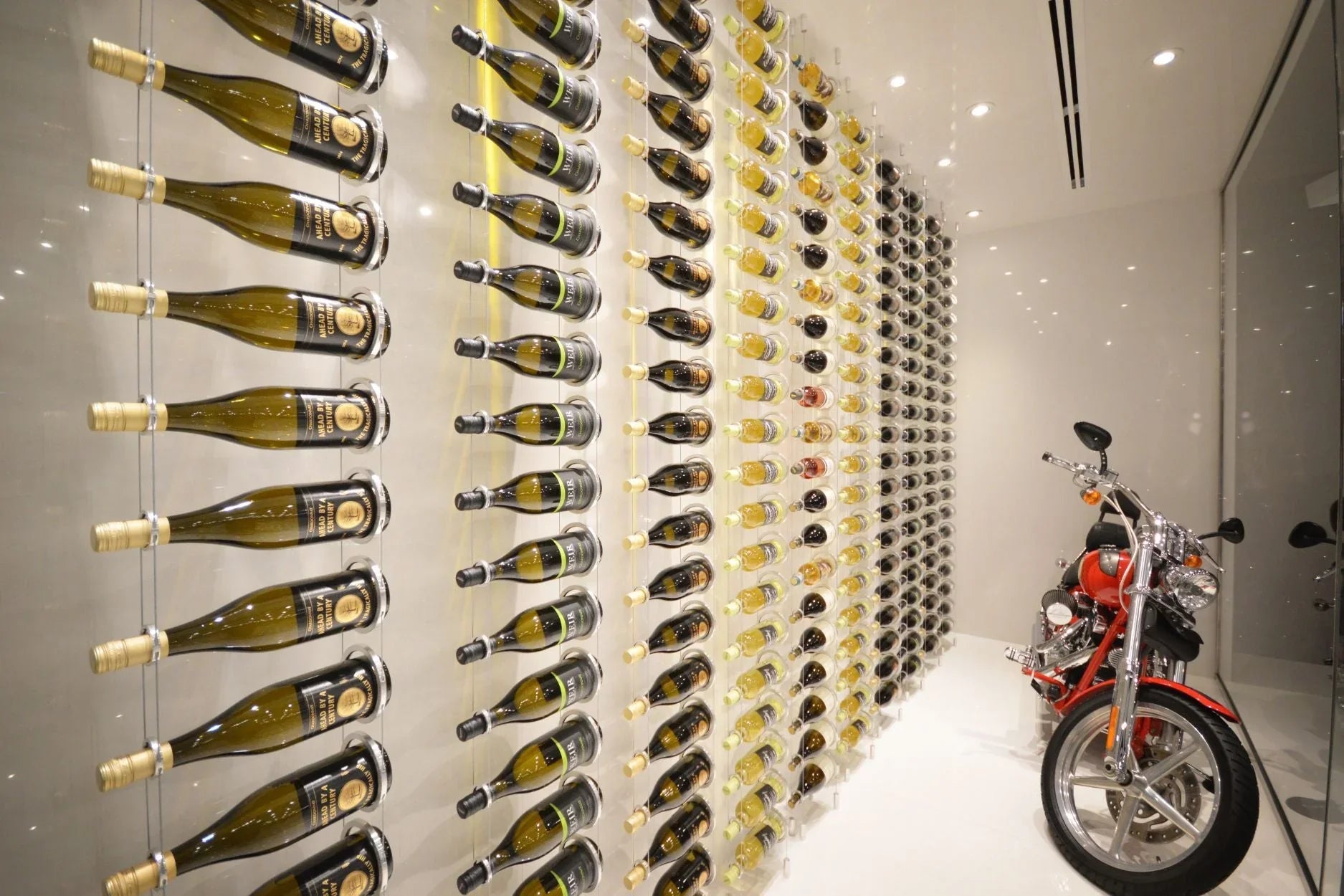 Modern wine cellar with wall-mounted wine racks and a red motorcycle on glossy floor