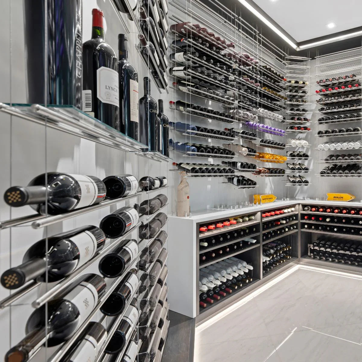 Modern glass and metal wine racks displaying bottles in a luxury custom wine cellar