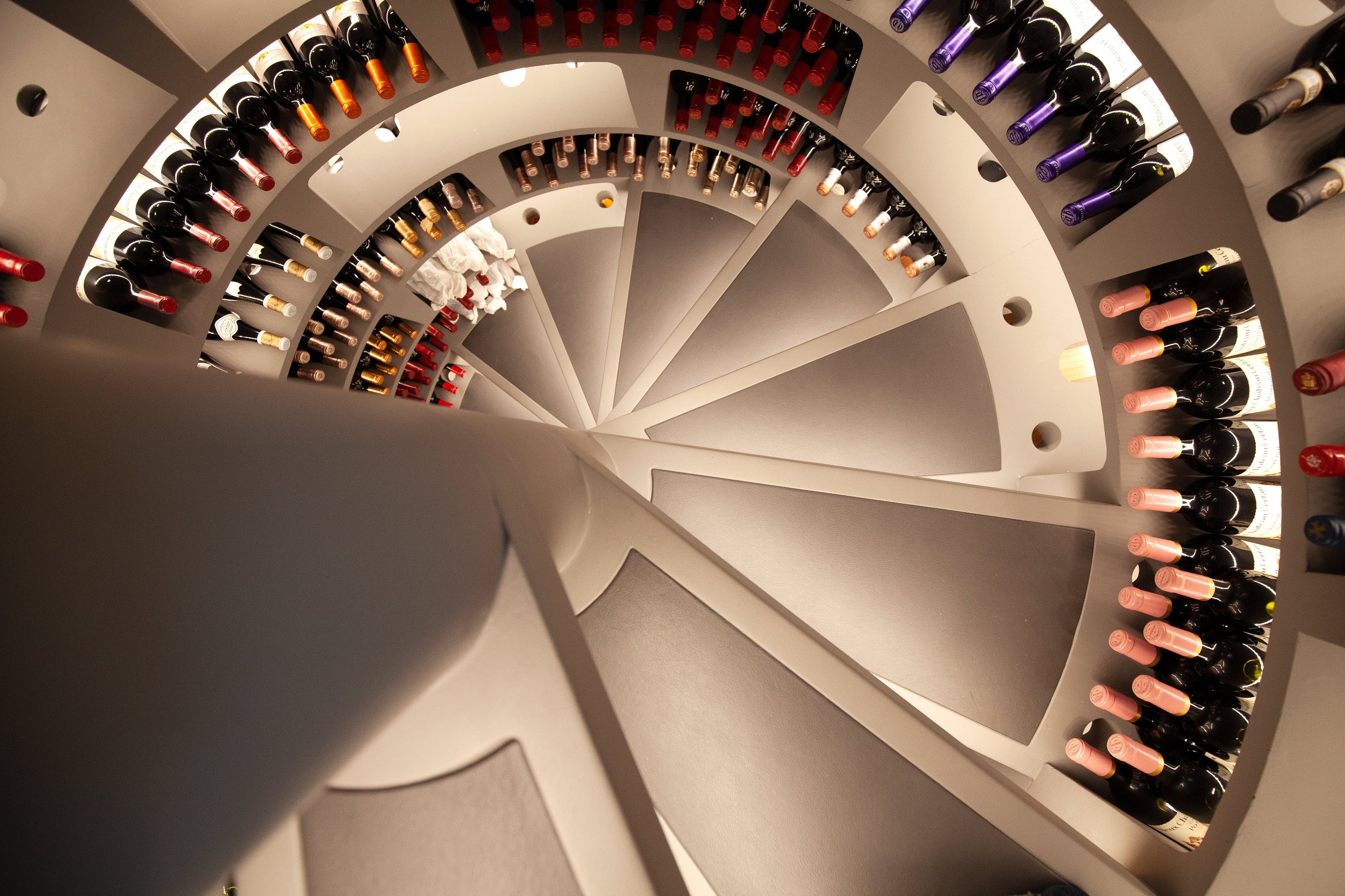 Spiral wine rack with bottles of various types and colors.